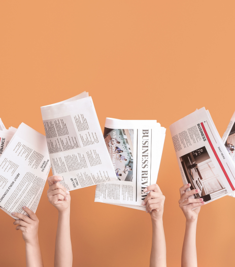 Mains tenant des journaux d’actualité sur fond orange