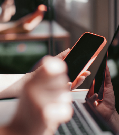 Personne tenant un smartphone devant un ordinateur portable