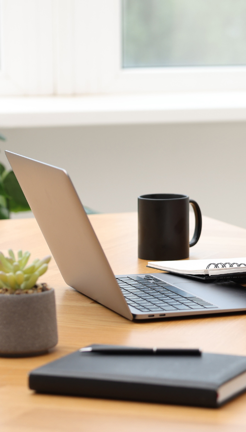 bureau en bois avec ordinateur, tasse de café noir et carnet