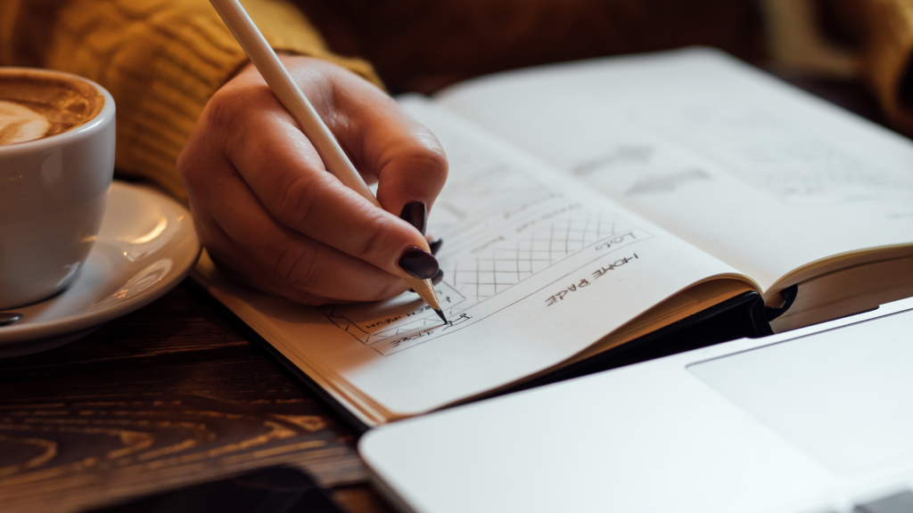 femme qui écrit sur son carnet devant un ordinateur