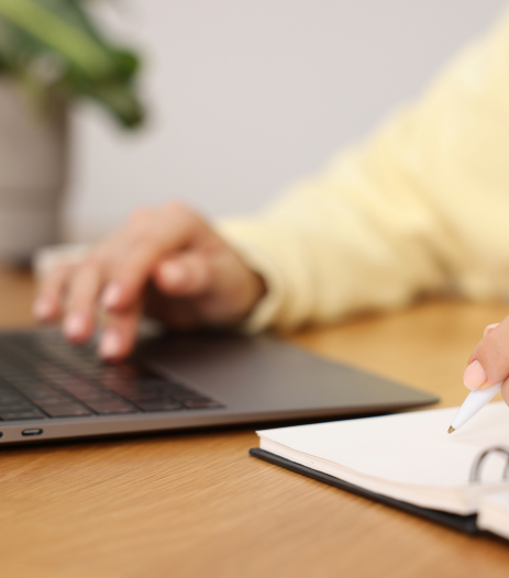 femme qui tient dans sa main un crayon et qui est sur son ordinateur