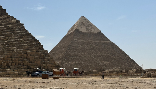 Deux pyramides d’Égypte dans le désert avec des calèches, des voitures et des visiteurs au pied du site